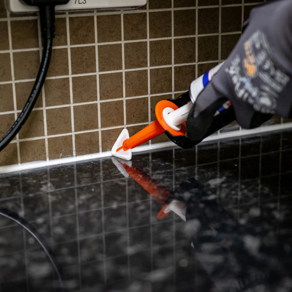 Person applying sealant to a kitchen counter